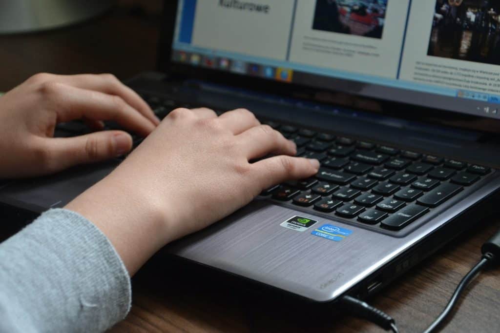 person typing on laptop over the shoulder