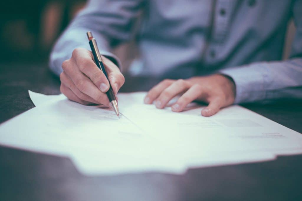 man signing contracts with a pen